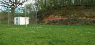 Zu sehen ist eine grüne Wiese und  einen Hügel. Auf der Wiese steht ein Fußballtor. Hinter dem Tor befindet sich ein Gitter, um zu verhindern, dass der Ball in der Landschaft verloren geht.